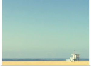 Life guard tower on beach with blue ocean and blue sky.