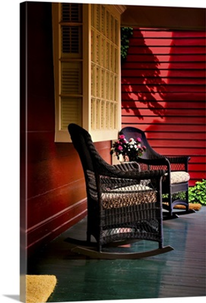 An American front porch with wooden boarding and two whicker rocking chairs